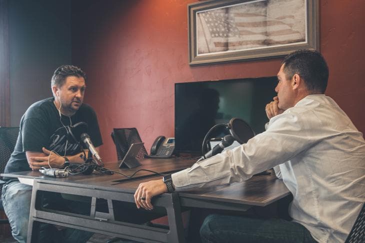 Two men recoding a podcast on a table
