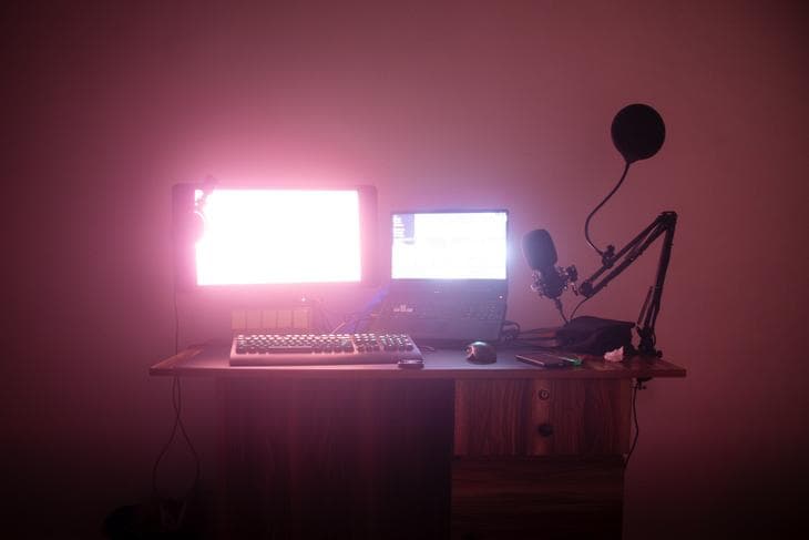 Laptop with widescreen connected on a desk next to a microphone with a pop filter