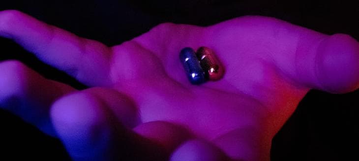 Hand holding blue and red capsules like in the movie The Matrix