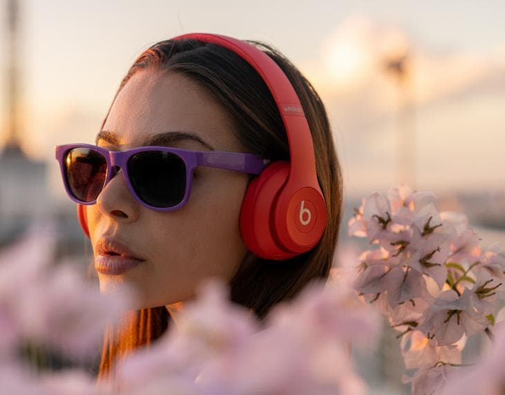 Woman wearing purple sunglasses and using red headphones
